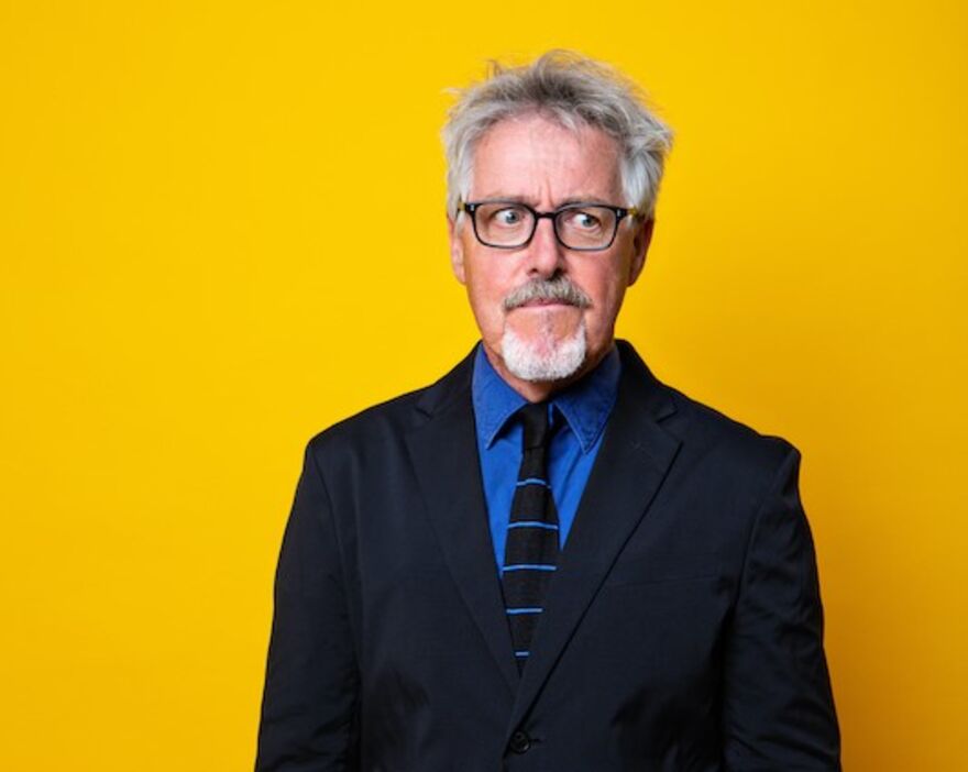 Griff Rhys Jones in a suit with a yellow background