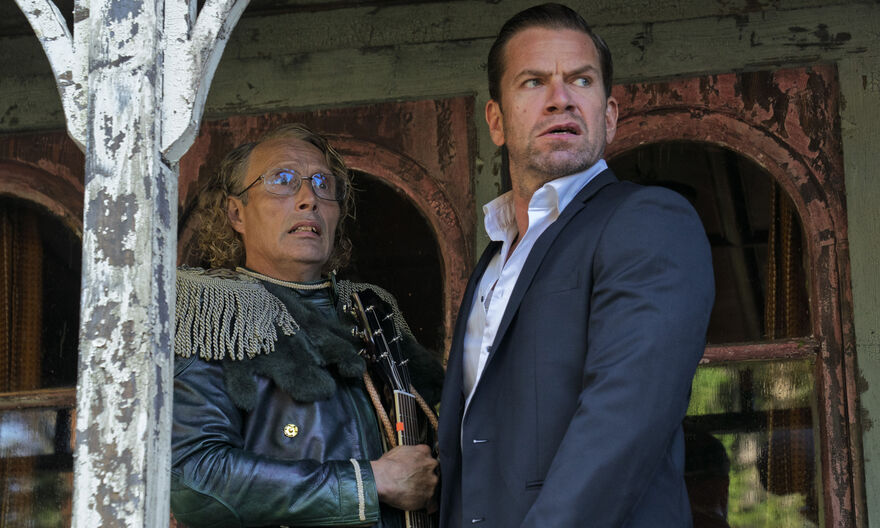 Two brothers stand together on a veranda looking alarmed. 