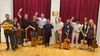 A group of people holding guitars and waving