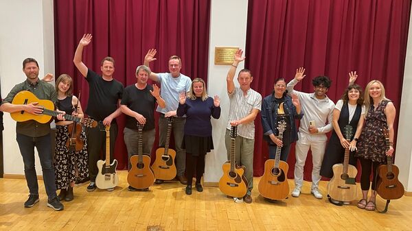 A group of people holding guitars and waving