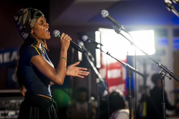 A young woman sings passionately into a microphone during a live performance.