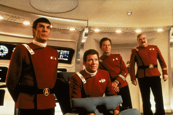 A group of four men in red uniforms on board a spaceship. 