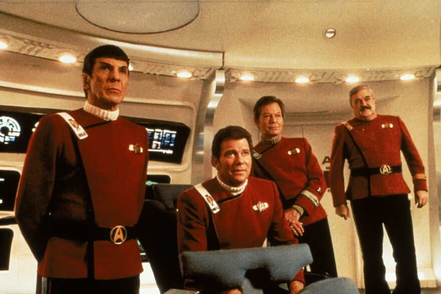 A group of four men in red uniforms on board a spaceship. 