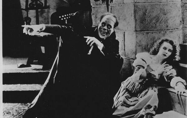 Man in a robe crouched pointing with a woman on the floor leaning across stairs