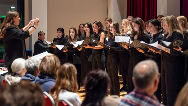 Chamber Choir holding music and singing being led by a conductor