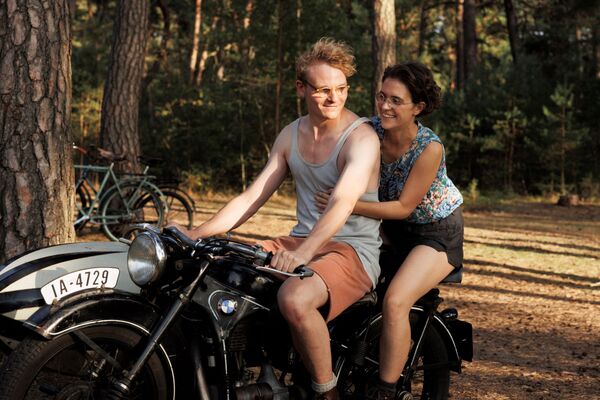 A young couple ride on a motorbike together.