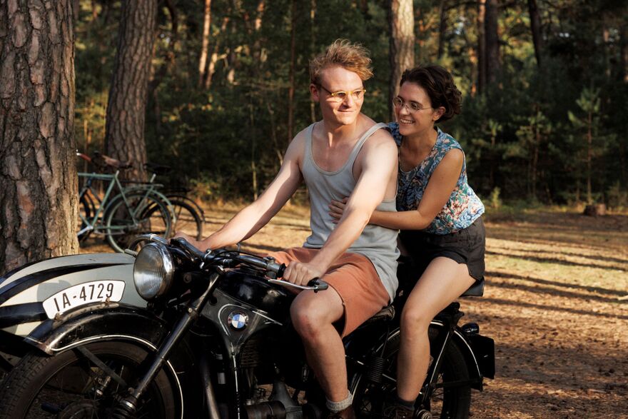 A young couple ride on a motorbike together.