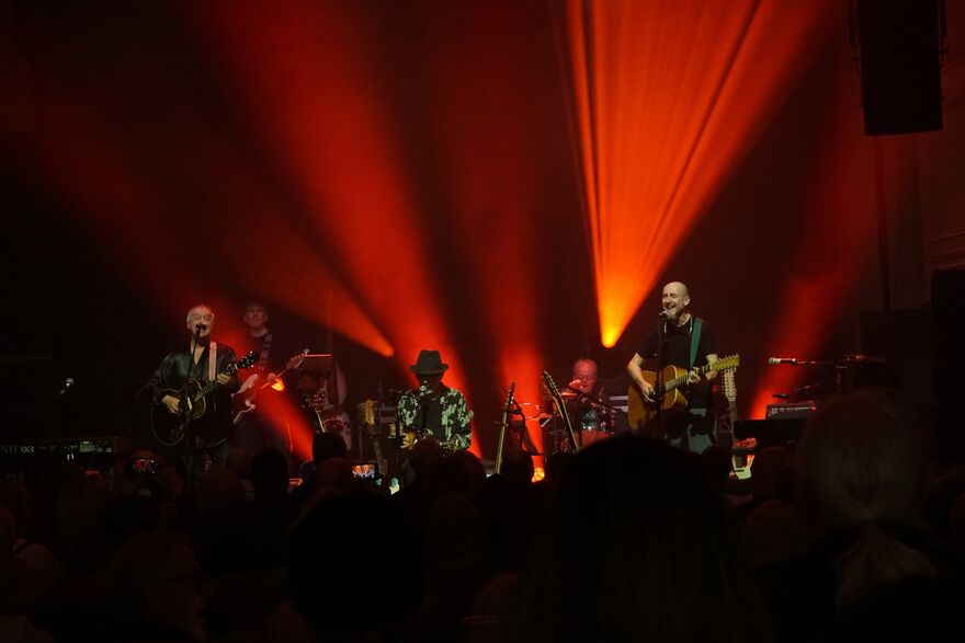 Band on stage with orange lights pointing upwards 