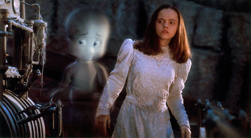 A young teenage girl wearing a bridal dress stands next to Casper the friendly ghost. 