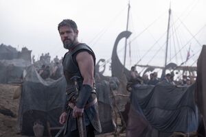 Matt Damon as Odysseus surrounded by boats on a beach. 