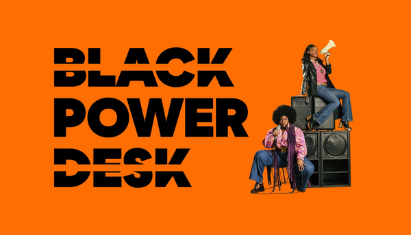Two women sat on large speakers one is holding a megaphone 'Black Power Desk' in large letters on the left handside on a bright orange background