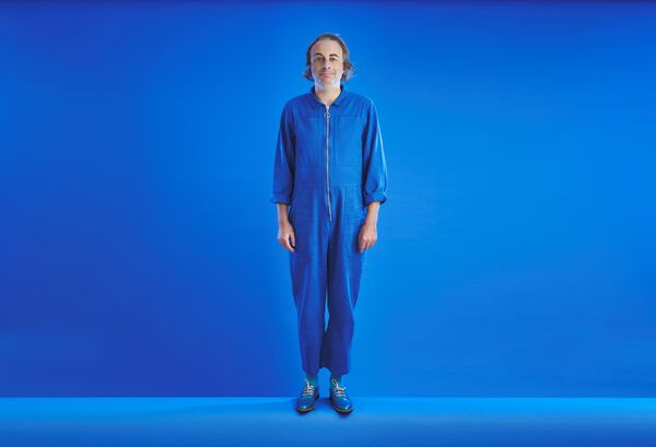 Man stood in a blue boilersuit on a blue background