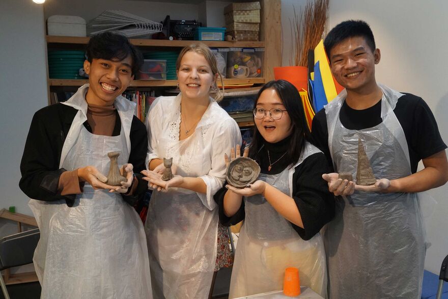 A group of students holding the clay sculptures they have made