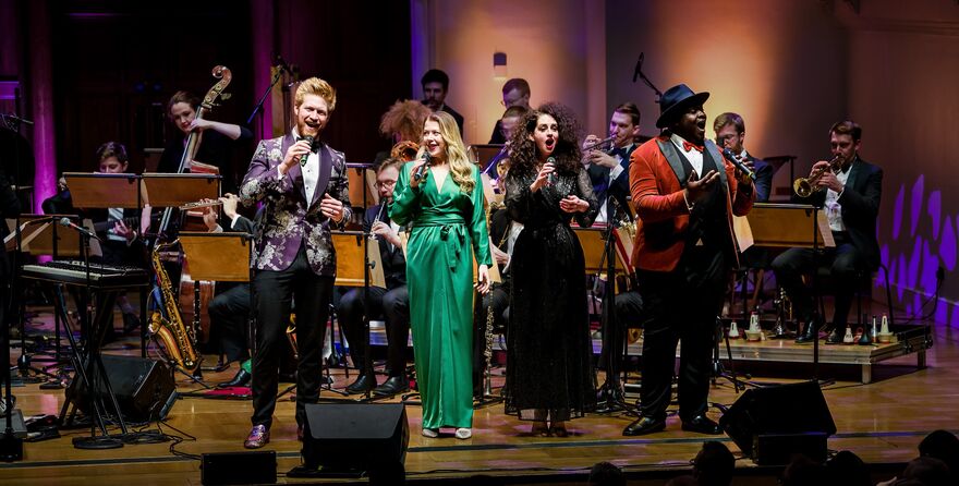 4 Singers on stage with a swing orchestra behind them