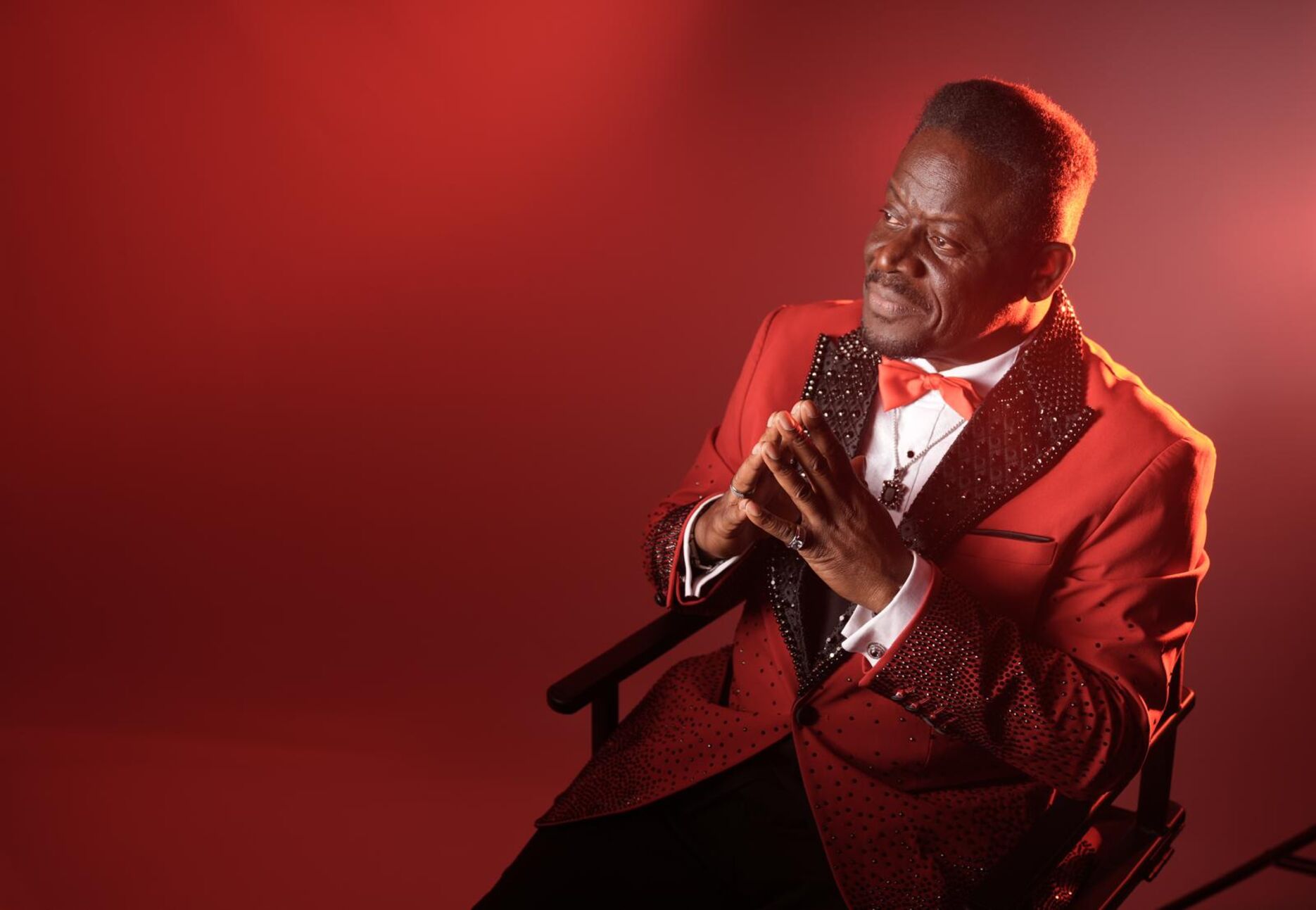 Harry Cambridge in a red tuxedo sat down with his hands together