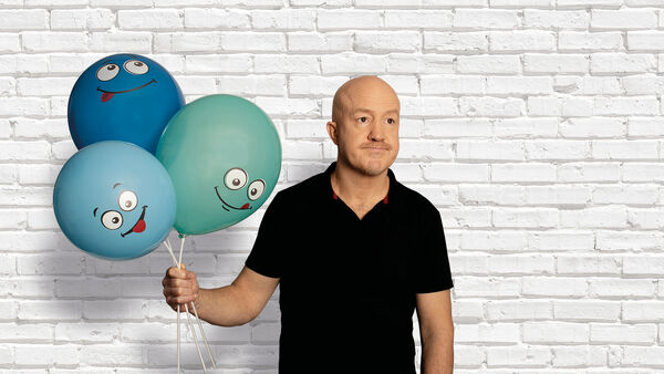 Andy Parsons holding three balloons with faces on