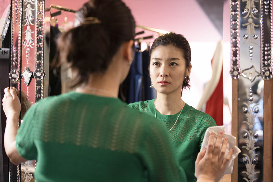 A woman looks at her reflection in a shop mirror. 