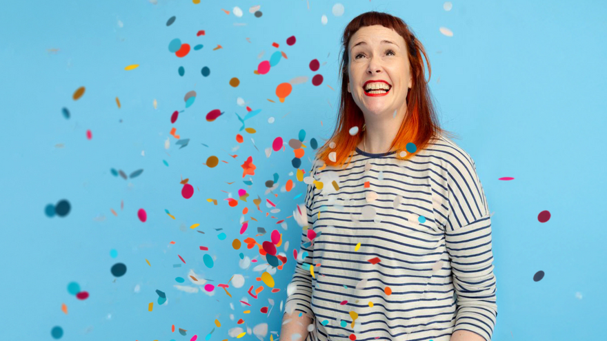 A woman smiling with confetti falling in front 