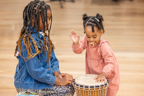 Two young girls sat playing drum