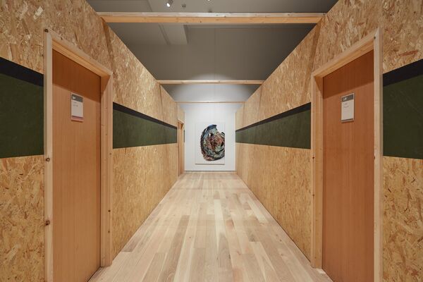 Long plywood corridor with a painting at the end of it
