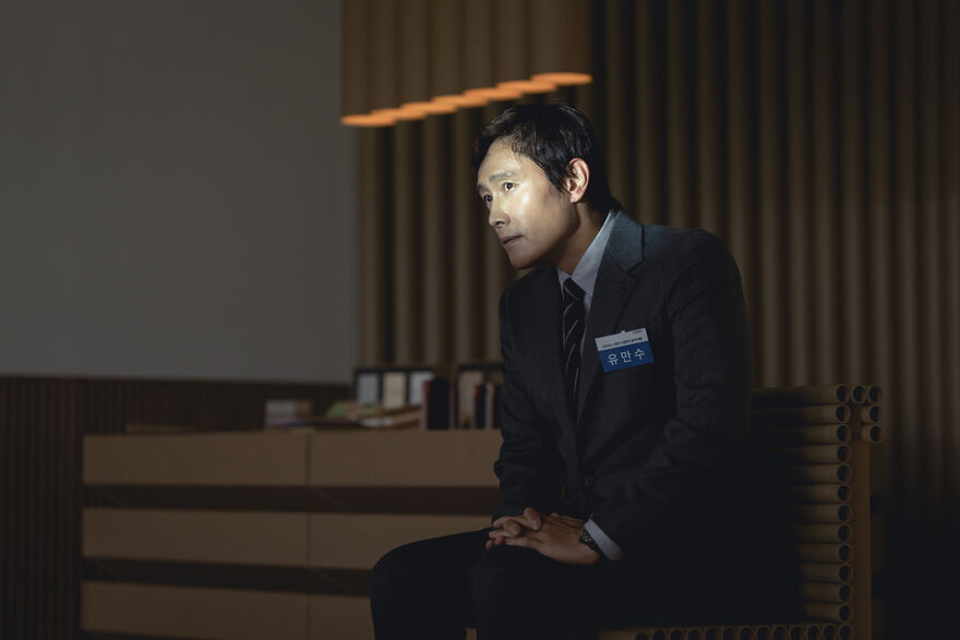 A man sits in an interview with light shining on his face. 