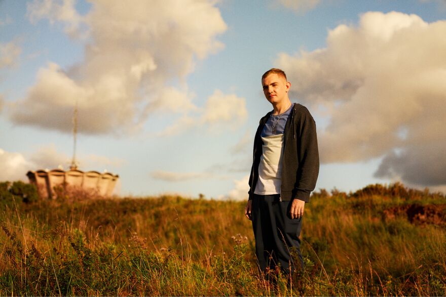 A young man stood in an overgrown field