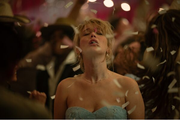 Jennifer Lawrence with her eyes closed looking up whilst confetti falls around her