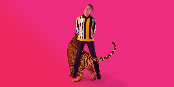 Chris Packaham with a tiger against a pink background