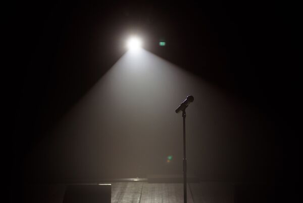 Dark stage with a wide beam light shining on a microphone