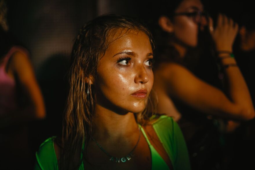 A young woman, in neon green clothing, glistens with sweat. 