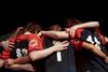 A group of girls wearing football kits hugging