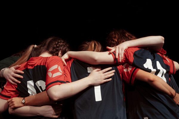 A group of girls wearing football kits hugging