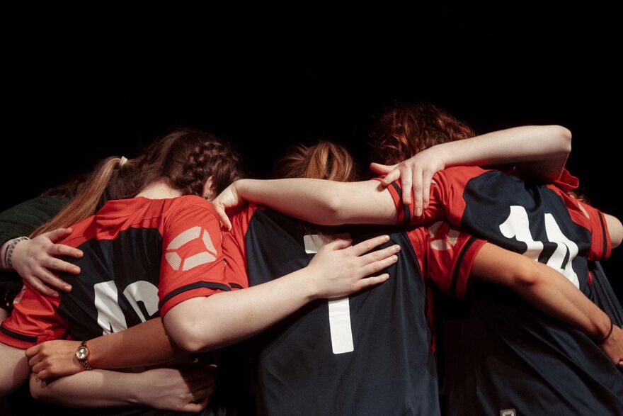 A group of girls wearing football kits hugging