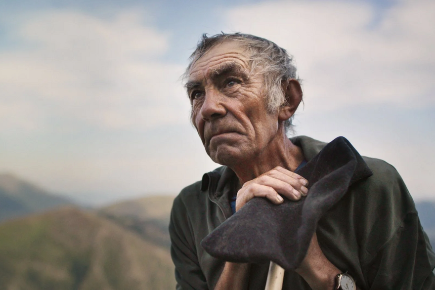 An old shepherd with out of focus mountains in the background
