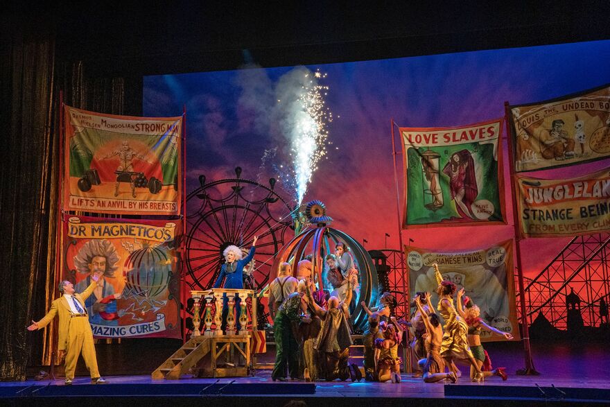 A fairground fills the stage. 