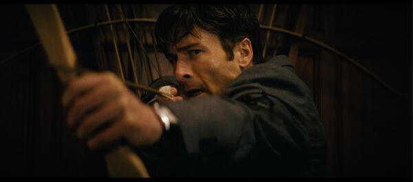 Glenn Powell drawing a bow and arrow