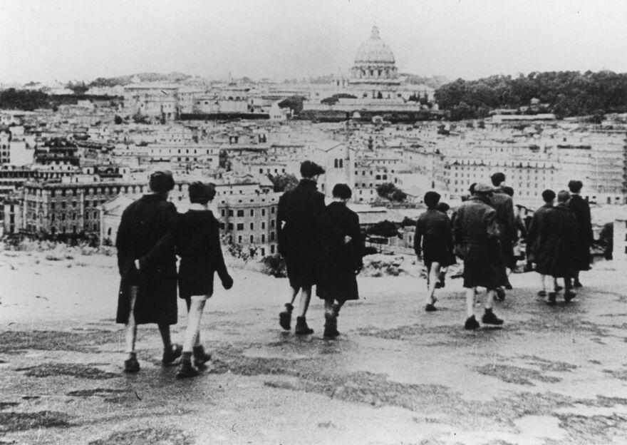 A black and white image of people working through Rome. 