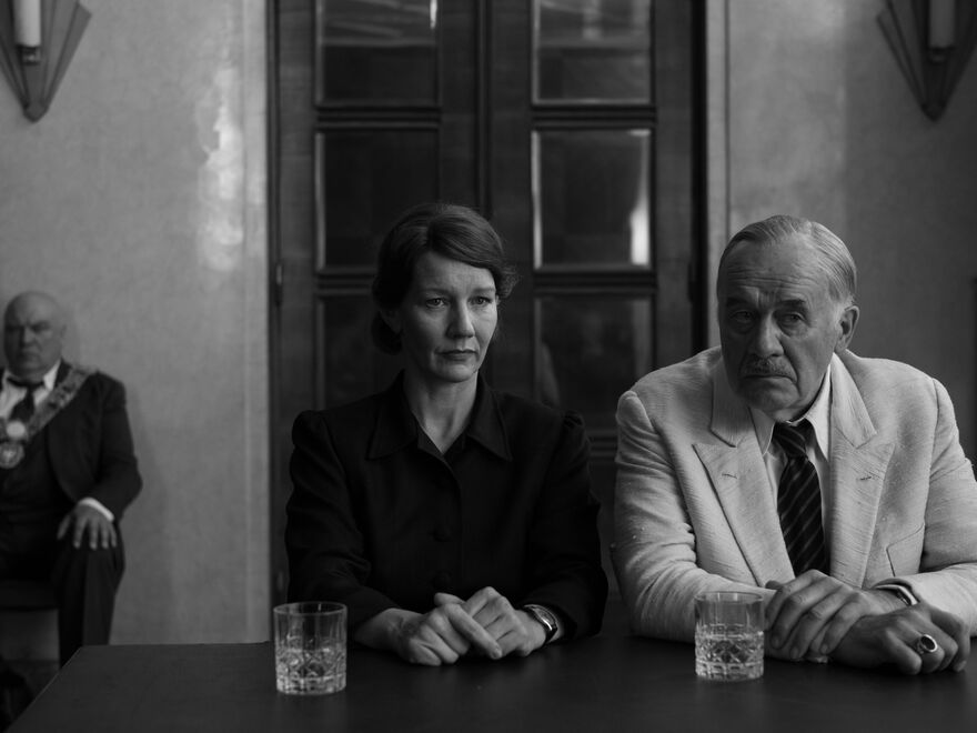 A black and white photo of a man and woman sitting at a table. 