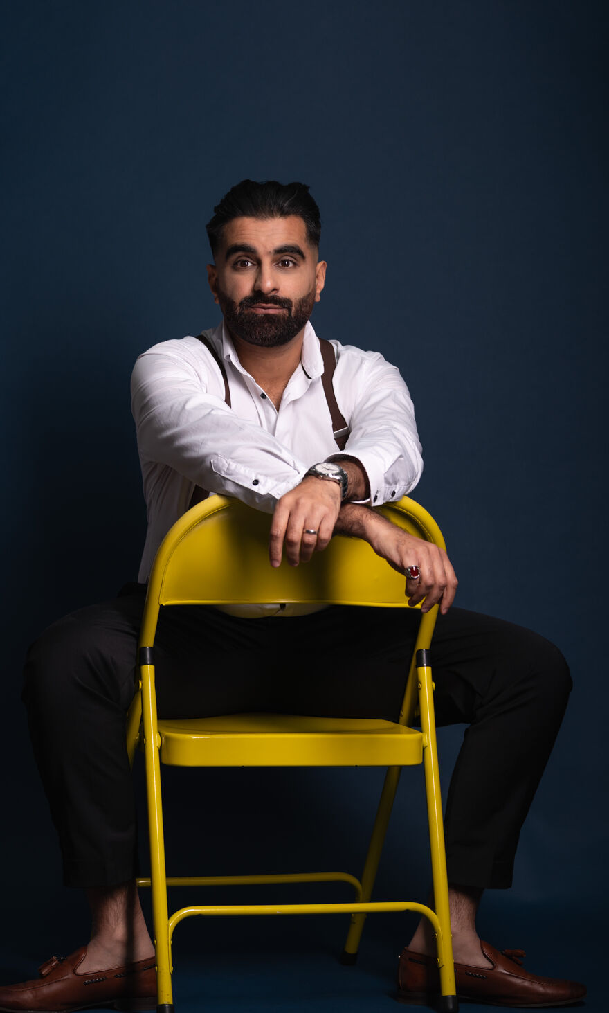 Tez Ilyas sat on a a backwards yellow chair