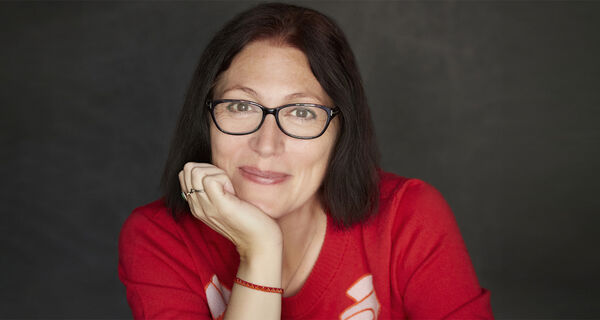 A portrait of author Natalie Haynes, resting her chin on her hand.