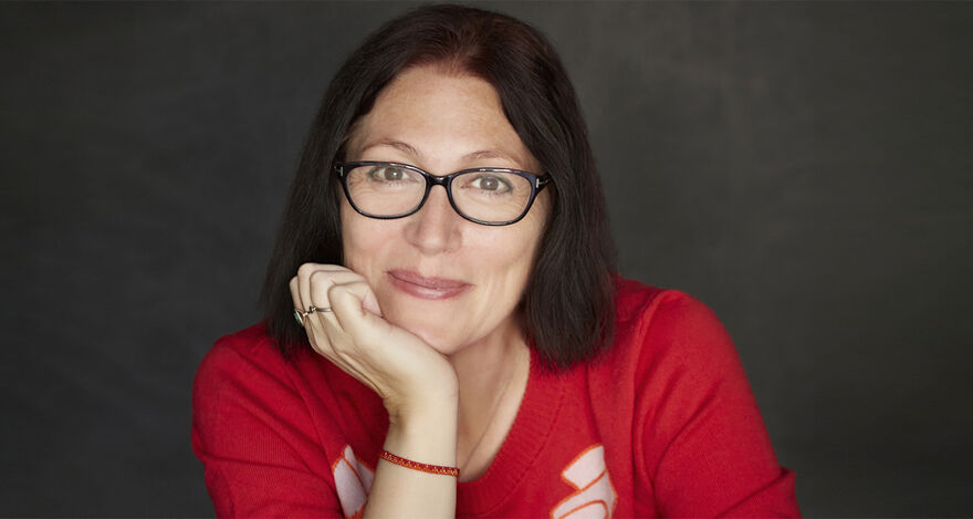 A portrait of author Natalie Haynes, resting her chin on her hand.