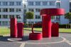 Large red sculpture with cylindrical forms outside on the University of Warwick campus 