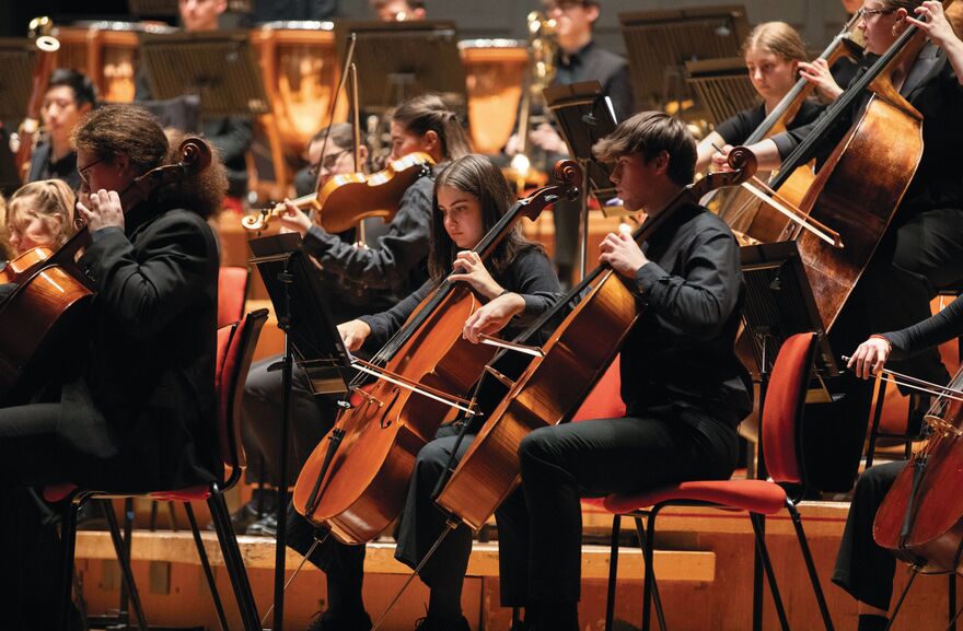 Young Orchestra sat playing string instruments