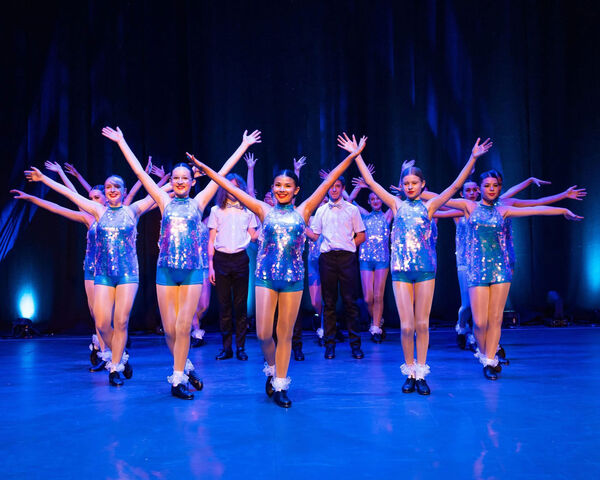 A group of dancers on stage with their arms in the air