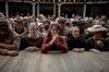A woman stands at the front of a crowd at the Globe theatre. 