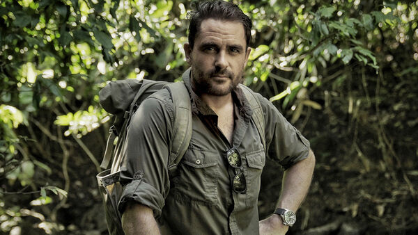 Levison Wood in a green shirt with a backpack in a forest