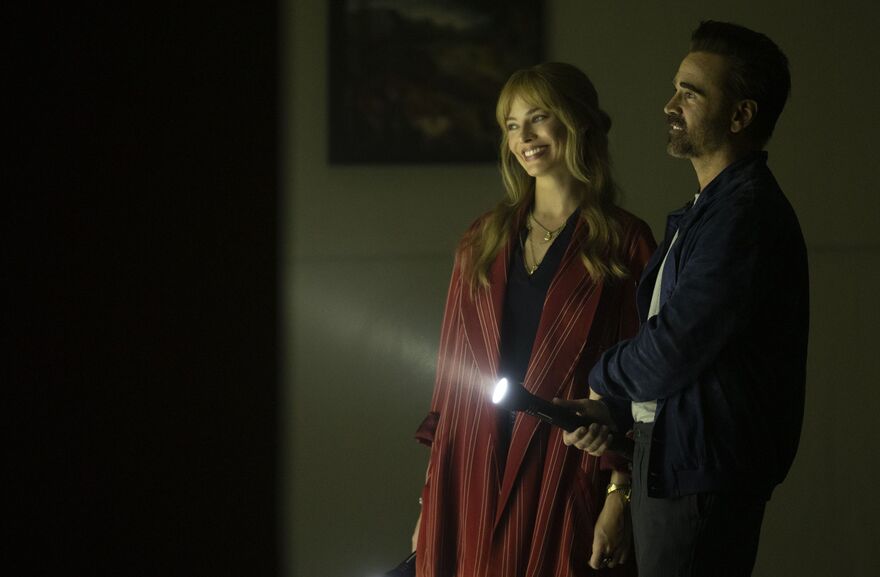 A man and woman smile widely as they approach a door.