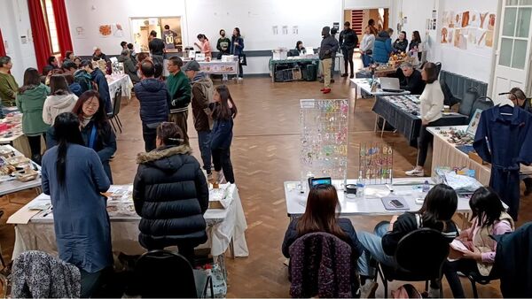 People browsing craft, gift, and book stalls inside a maker's market hall.