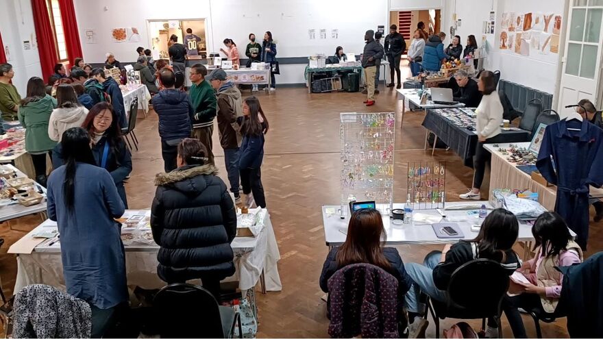 People browsing craft, gift, and book stalls inside a maker's market hall.