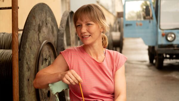 A seated woman smiles whilst looking over her shoulder. 